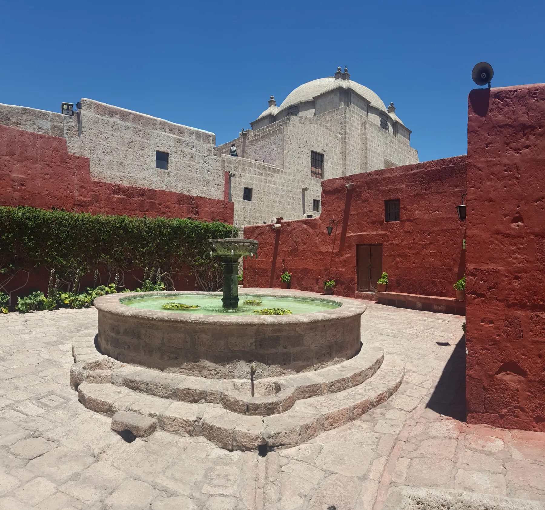 Een fontein tussen rode muren en een lichte koepel in Santa Catalina, Arequipa.